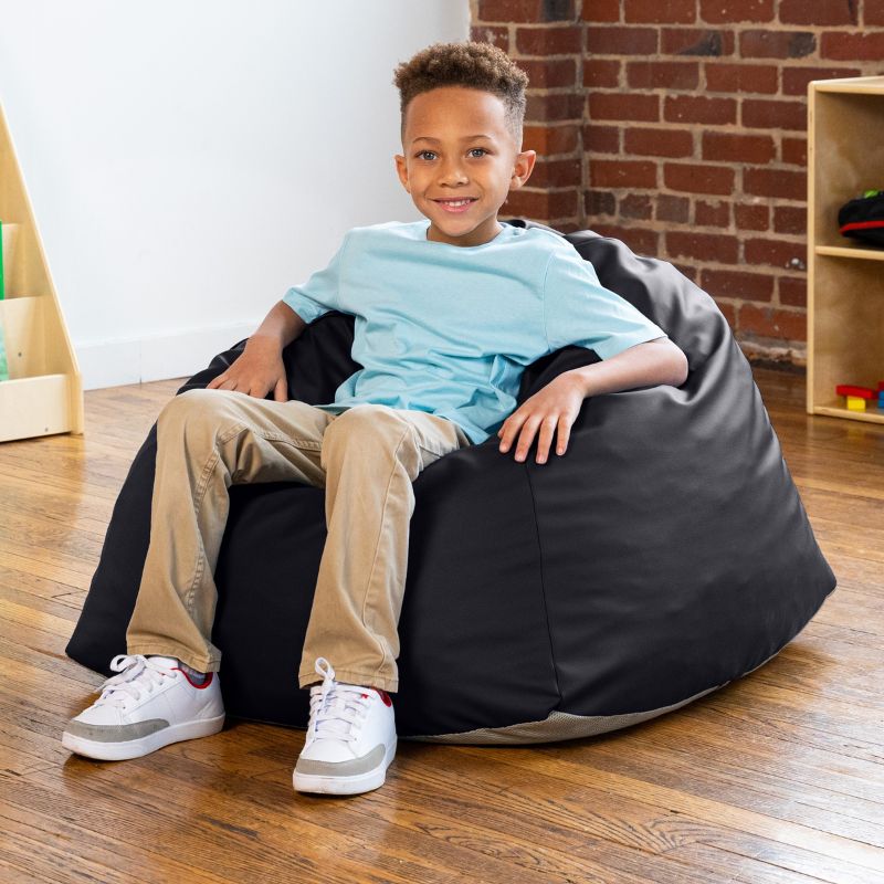 Boy sitting in a black Jaxx Gumdrop bean bag chair in a classroom setting