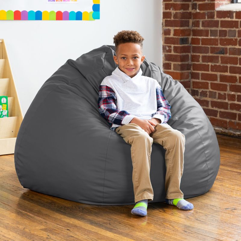 Boy sitting on a charcoal Jaxx Gumdrop kids bean bag chair in a classroom