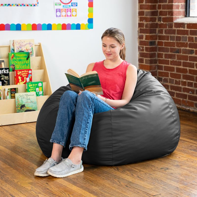 Teen reading in a black Jaxx Gumdrop kids bean bag chair in a classroom reading nook