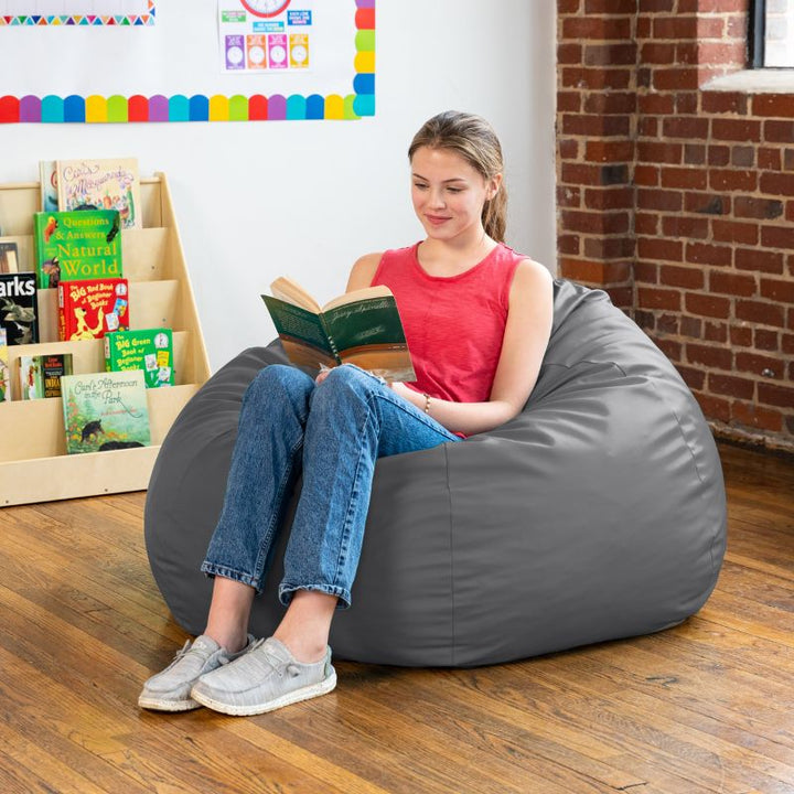 Teen reading in a charcoal Jaxx Gumdrop kids bean bag chair in a classroom reading nook