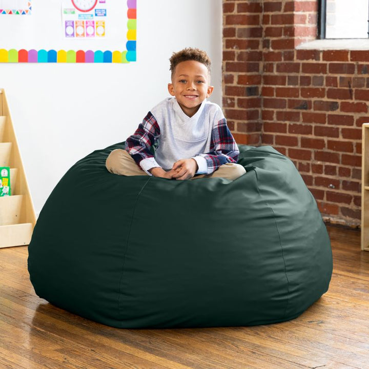 Child sitting on a forest green Jaxx Gumdrop kids bean bag chair in a classroom