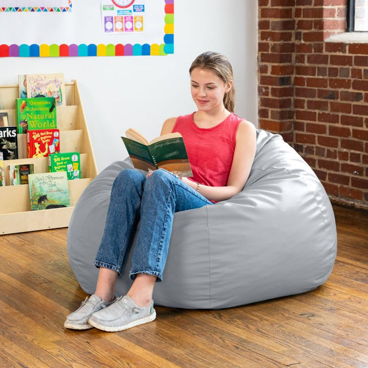 Teen reading in a grey Jaxx Gumdrop kids bean bag chair in a classroom reading nook