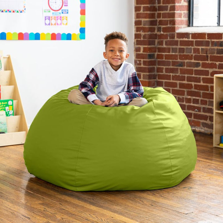 Child sitting on a lime green Jaxx Gumdrop kids bean bag chair in a classroom