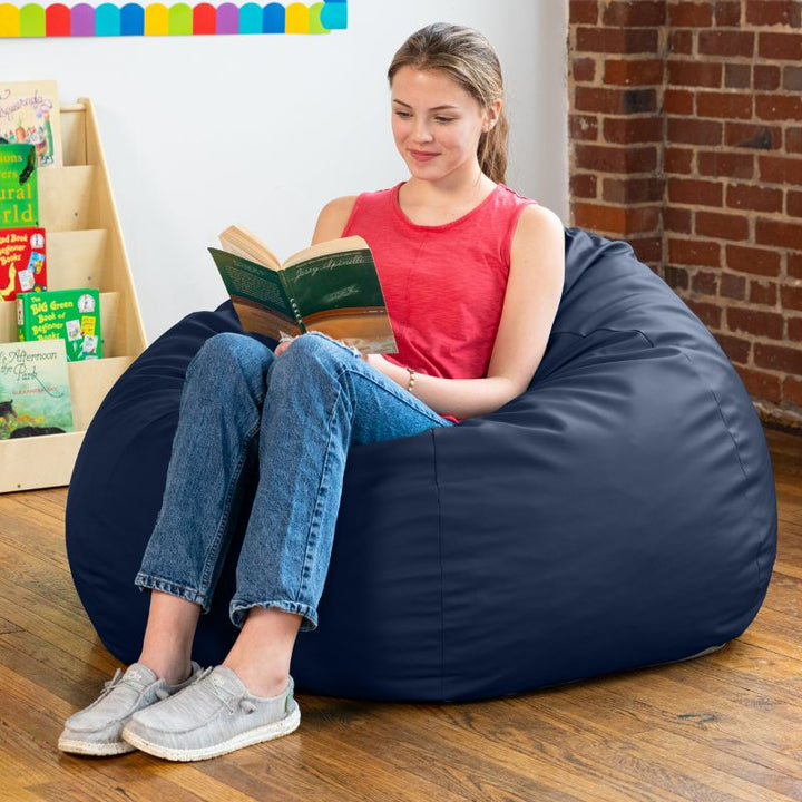Teen reading in a navy blue Jaxx Gumdrop kids bean bag chair in a classroom reading nook