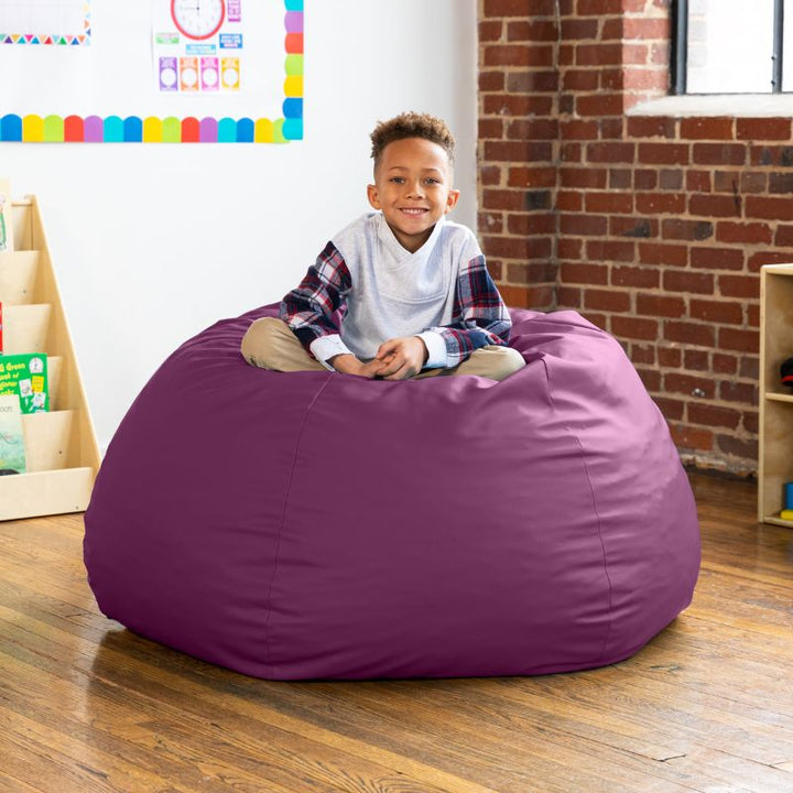 Child sitting on a purple Jaxx Gumdrop kids bean bag chair, wipeable classroom seating