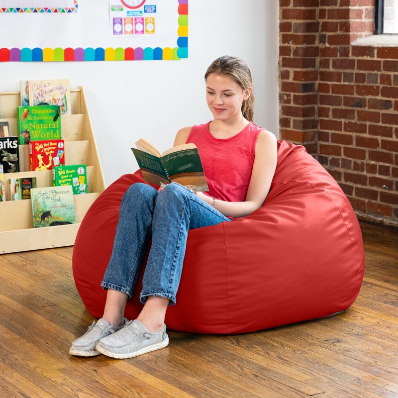 Teen reading in a red Jaxx Gumdrop kids bean bag chair in a classroom reading nook