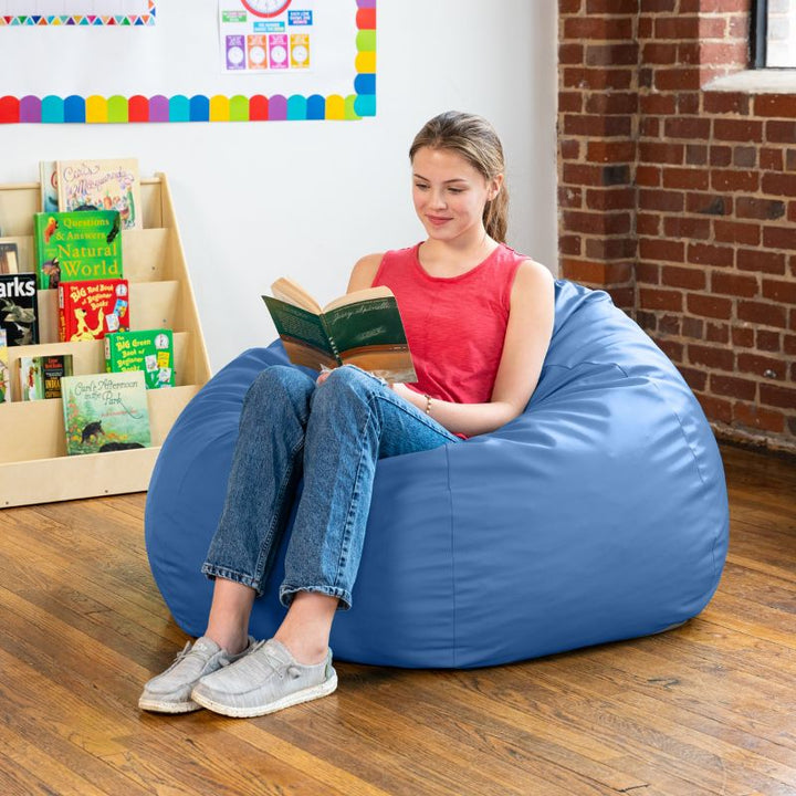 Teen reading in a royal blue Jaxx Gumdrop kids bean bag chair, flexible classroom seating