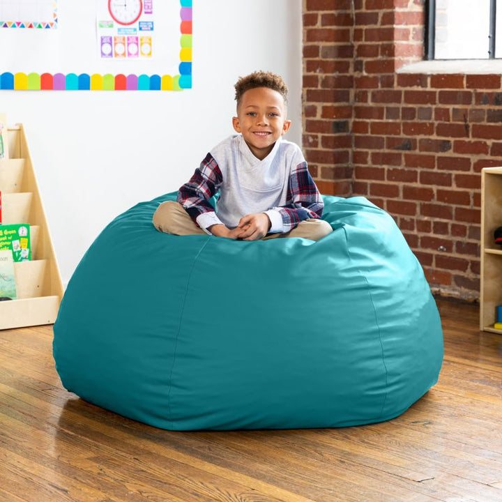 Child sitting on a teal Jaxx Gumdrop kids bean bag chair in a classroom setting