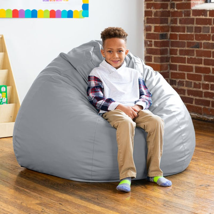 Boy sitting on a grey Jaxx Gumdrop kids bean bag chair, wipeable classroom seating