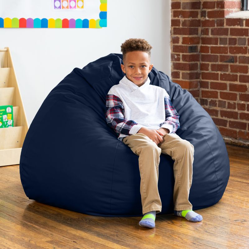 Boy sitting on a navy blue Jaxx Gumdrop kids bean bag chair, foam-filled classroom seating