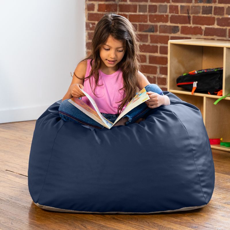 Girl reading a book while seated on a navy Jaxx Gumdrop bean bag chair in a classroom