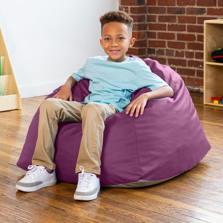 Boy sitting in a purple Jaxx Gumdrop bean bag chair in a classroom setting