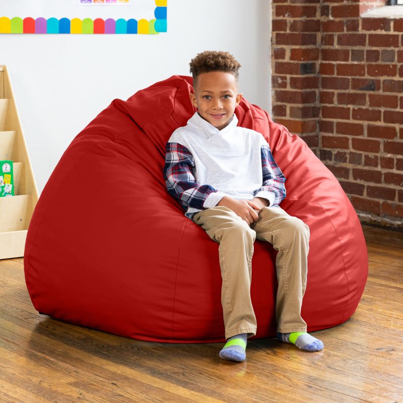 Boy sitting on a red Jaxx Gumdrop kids bean bag chair, durable classroom seating