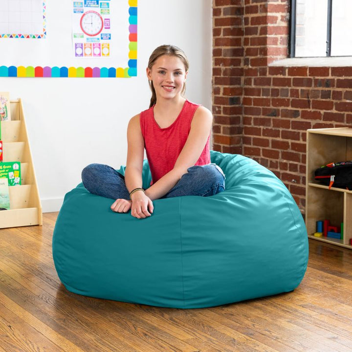 Teen sitting cross-legged on a teal Jaxx Gumdrop kids bean bag chair, flexible classroom seating