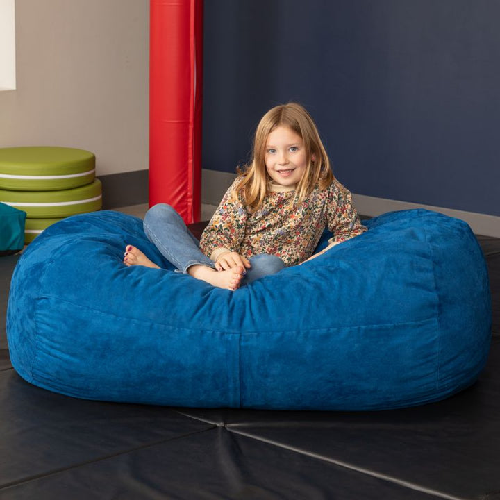 Child sitting on the Jaxx Lounger 4ft bean bag chair in Blue microsuede, a washable deep pressure sensory seat
