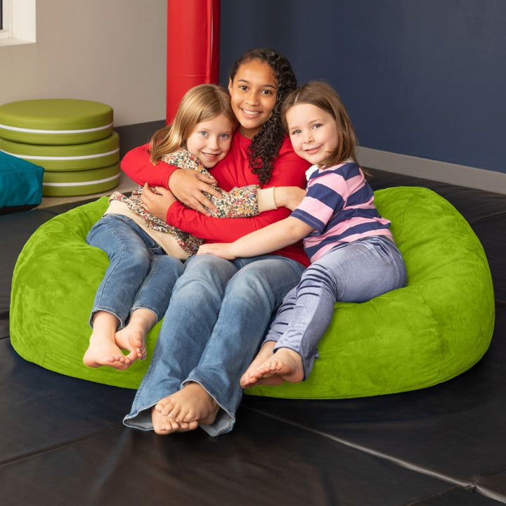 Three children sharing the Jaxx Lounger 4ft bean bag chair in Green microsuede, a roomy sensory seat for kids