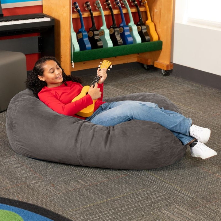 Teen reclining with a ukulele on the Jaxx Lounger 4ft bean bag chair in Grey microsuede, a washable calm corner seat