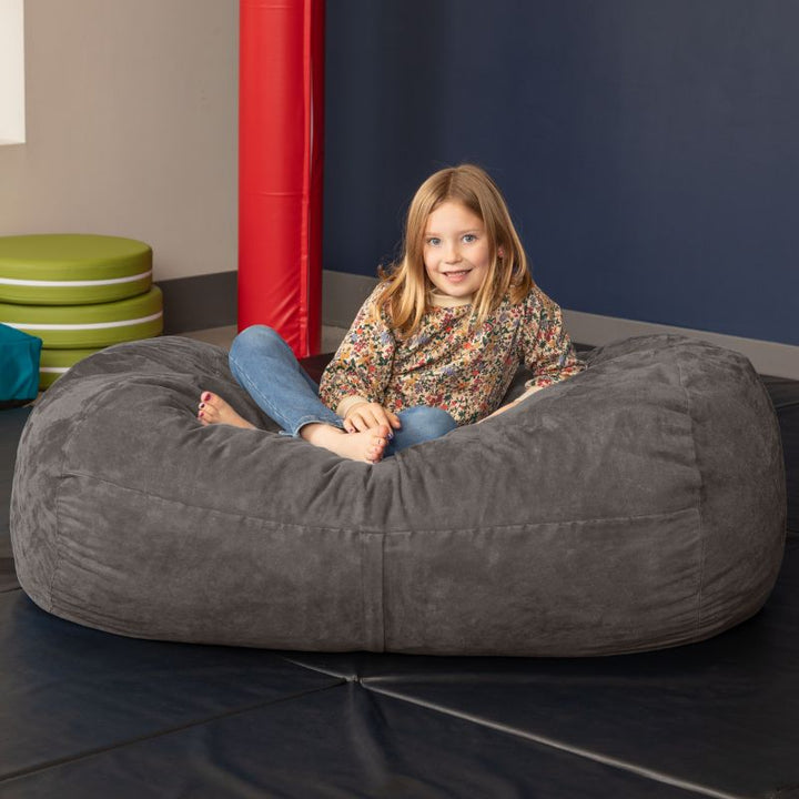 Child sitting on the Jaxx Lounger 4ft bean bag chair in Grey microsuede, a washable sensory room seat