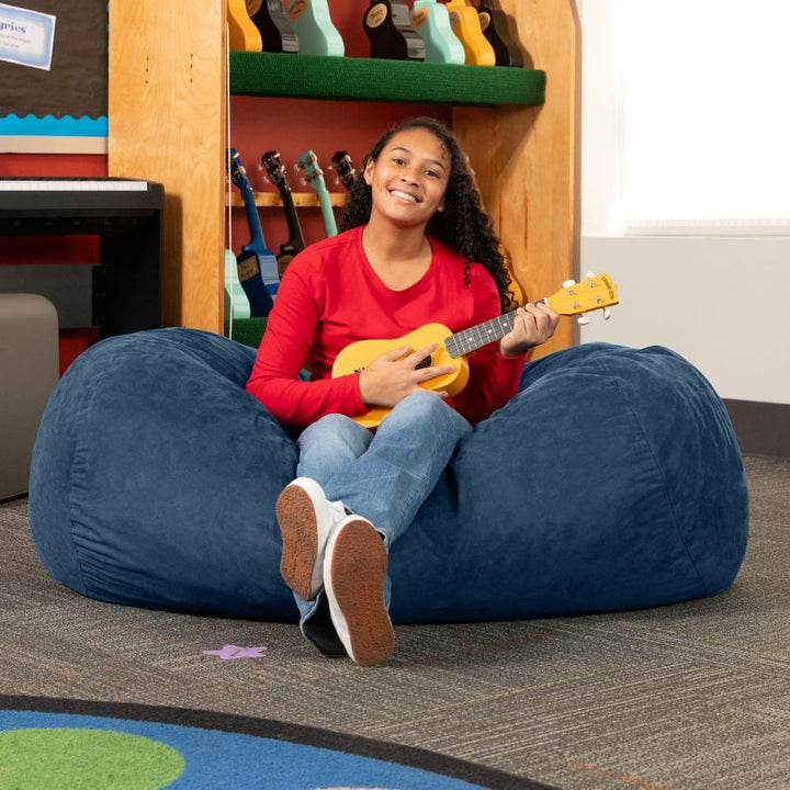 Teen playing ukulele on the Jaxx Lounger 4ft bean bag chair in Navy microsuede, a washable deep pressure seat