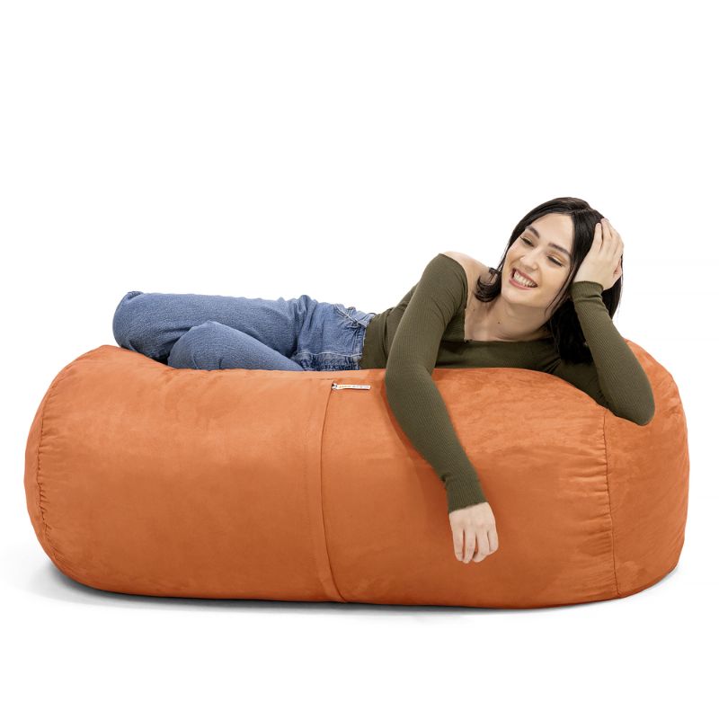 Woman leaning back on the Jaxx Lounger 4ft bean bag chair in Orange microsuede, a washable calm corner seat