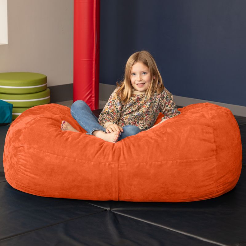 Child sitting on the Jaxx Lounger 4ft bean bag chair in Orange microsuede, a washable deep pressure sensory seat
