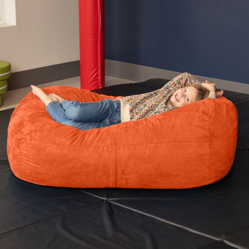 Child relaxing on the Jaxx Lounger 4ft bean bag chair in Orange microsuede, a washable deep pressure seat