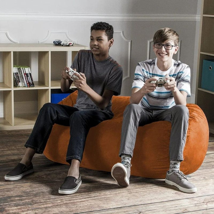 Two boys sharing the Jaxx Lounger 4ft bean bag chair in Orange microsuede while gaming, a roomy washable seat for kids