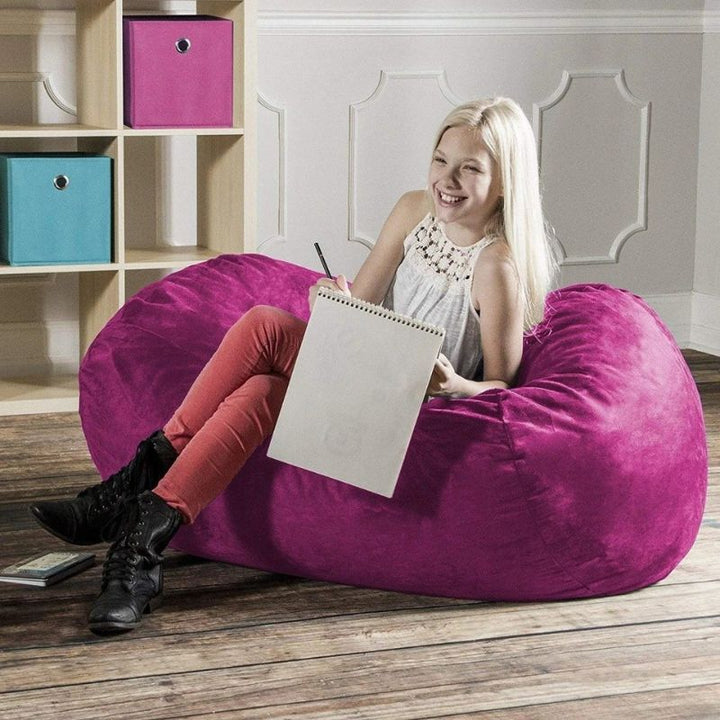 Girl drawing while seated on the Jaxx Lounger 4ft bean bag chair in Pink microsuede, a cozy bedroom sensory seat