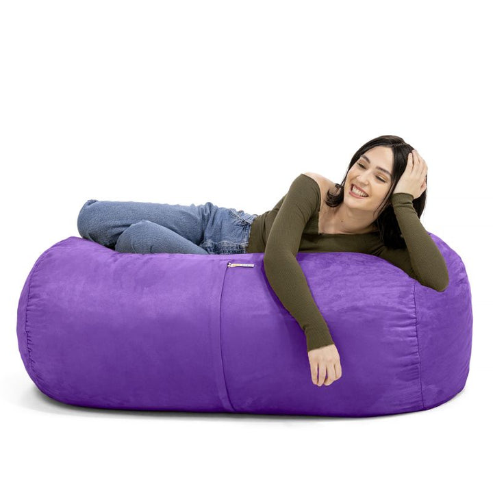 Woman leaning back on the Jaxx Lounger 4ft bean bag chair in Purple microsuede, a washable sensory seat