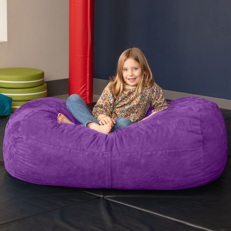 Child sitting on the Jaxx Lounger 4ft bean bag chair in Purple microsuede, a washable calm corner seat