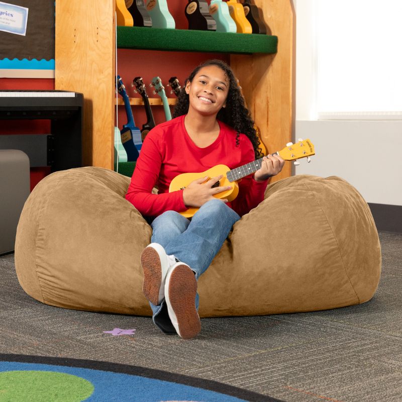 Teen playing ukulele on the Jaxx Lounger 4ft bean bag chair in Tan microsuede, a washable classroom seating option
