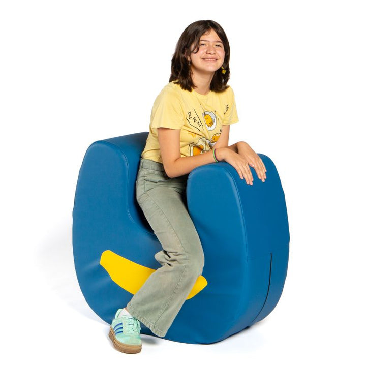 A child sitting inside the U-shaped opening of the Jaxx Zipline Loveseat, showing the seat's scale and shape