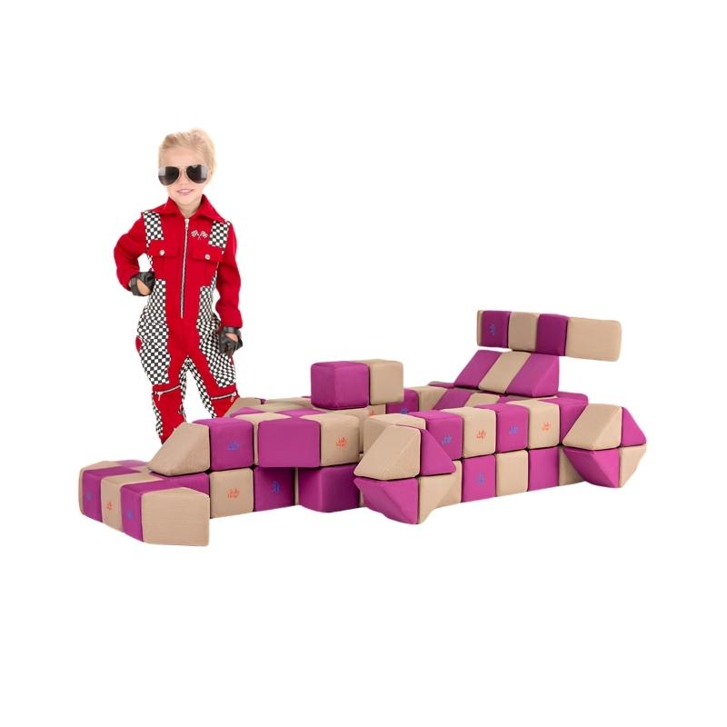 A child in a racing outfit stands next to a race car built from JollyHeap Basic Set magnetic foam blocks, demonstrating imaginative vehicle builds with this soft play block set.