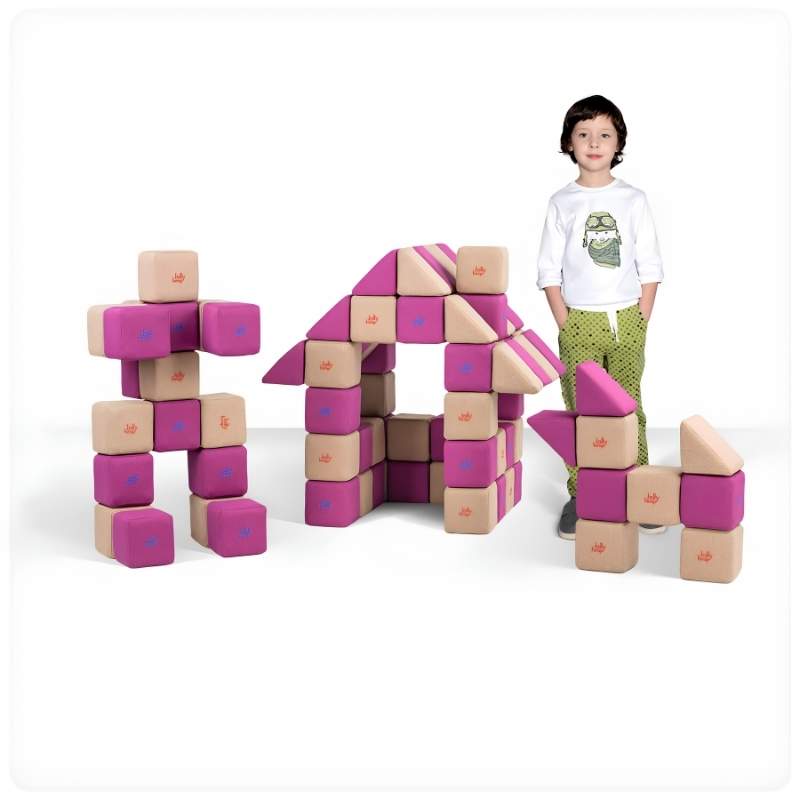 A boy stands beside a robot figure and a small house built from JollyHeap Basic Set magnetic foam blocks, showing the building range of this soft play set for schools and homes.