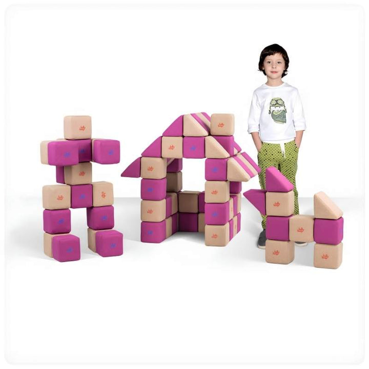 A boy stands beside a robot figure and a small house built from JollyHeap Basic Set magnetic foam blocks, showing the building range of this soft play set for schools and homes.