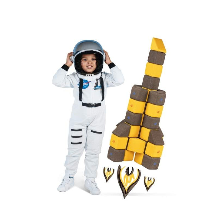 A child in an astronaut costume beside a rocket built from JollyHeap magnetic soft blocks with flame-shaped accents