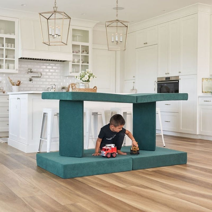 Child engaged in active fort play on the Kiddie Couch in Emerald Green, supporting gross motor development and sensory exploration