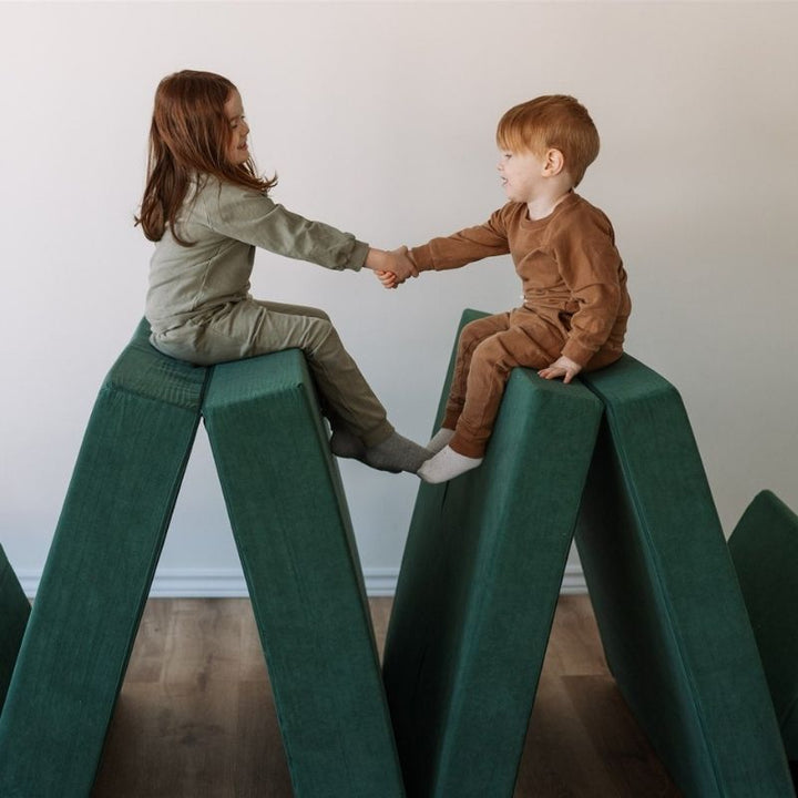 Children happily playing on the Kiddie Couch in Emerald Green, showing joyful active sensory play with the modular foam couch