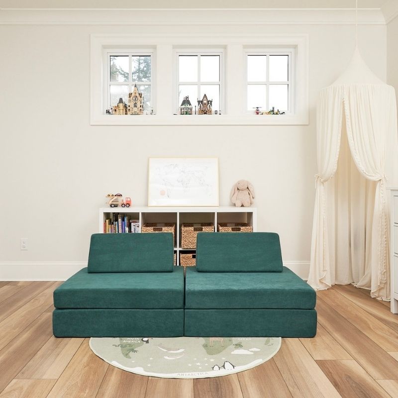 Front view of the Kiddie Couch in Emerald Green in a living room setting, showing the sensory play couch styled as home furniture