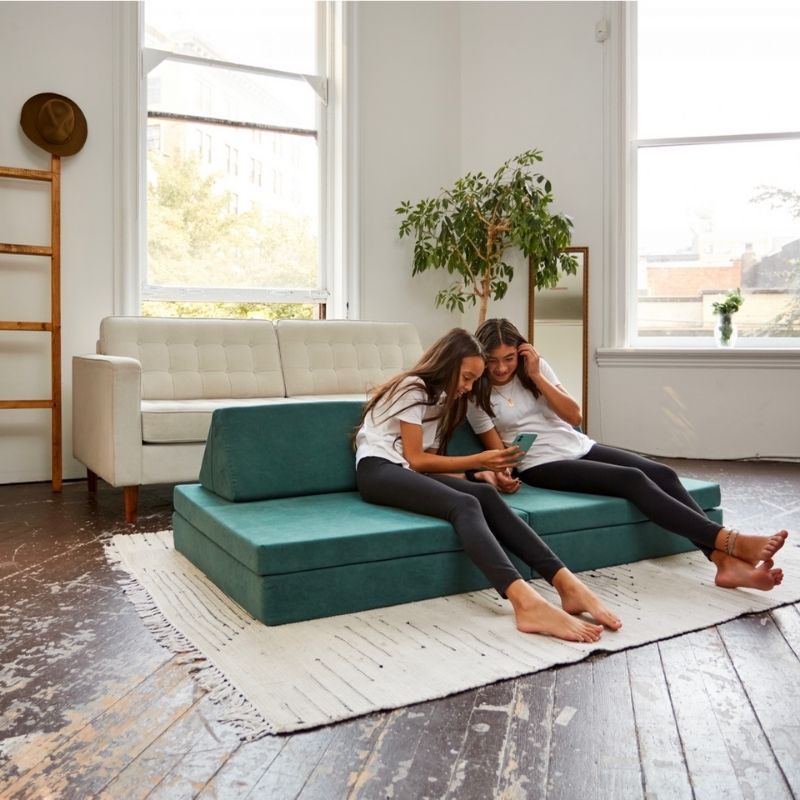 Two preteen girls relaxing on the Kiddie Couch in Emerald Green, showing the play couch as comfortable seating for older children