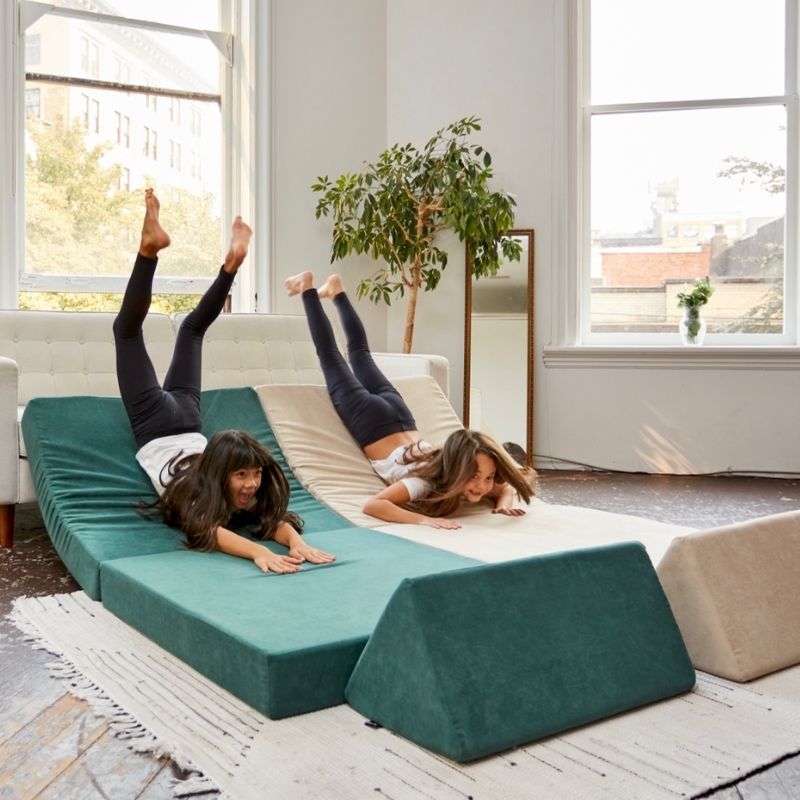 Child sliding on the Kiddie Couch sensory play couch in Emerald Green, engaging vestibular movement and gross motor development