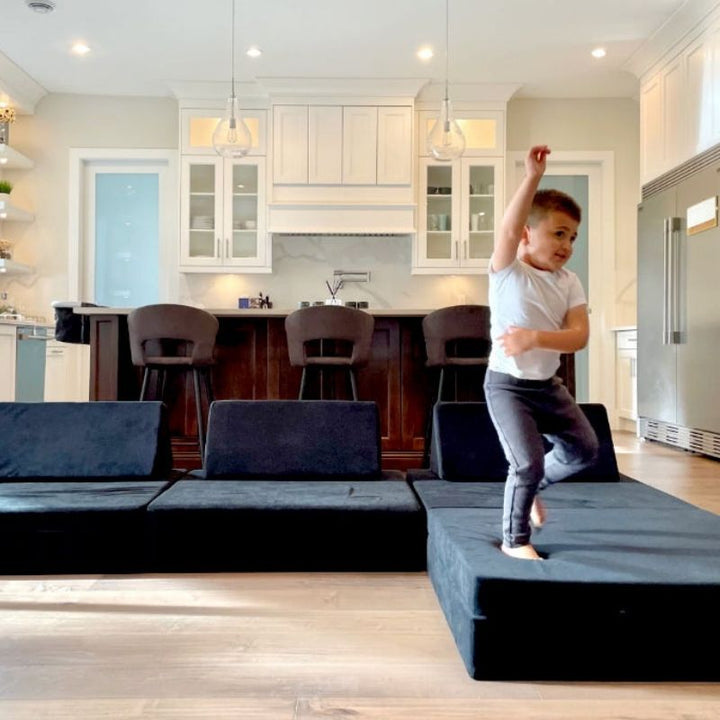 Child jumping on the Kiddie Couch in Jet Black, providing vestibular and proprioceptive input through active gross motor sensory play