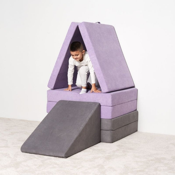 Child inside a fort built from the Kiddie Couch modular play couch in Orchid Purple, showing imaginative and enclosed sensory play