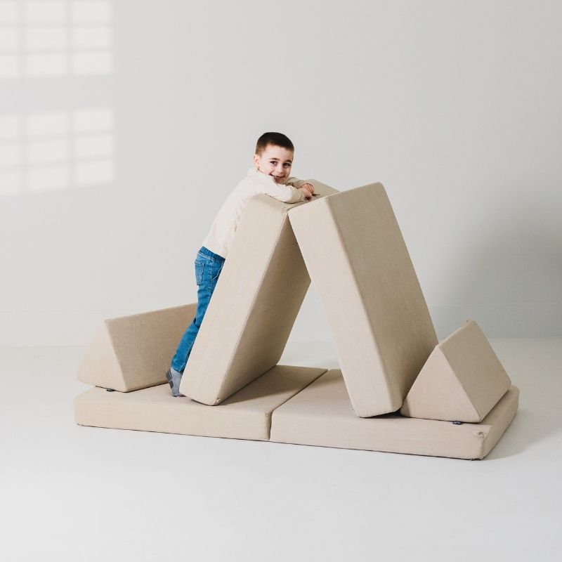 Child engaged in active play on the Kiddie Couch in Sand Beige, supporting gross motor development and sensory exploration