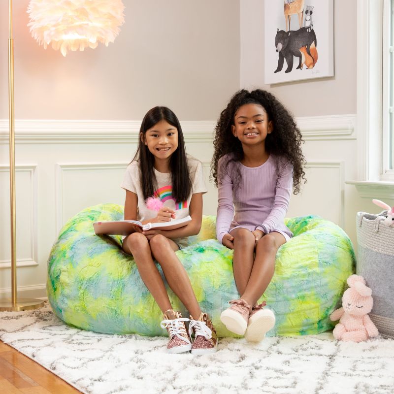 Two girls sit together on the Jaxx Lounger 4ft faux fur bean bag lounger for kids in Firefly, a bright sensory bean bag chair for shared play.