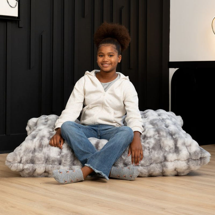 Girl seated on the CrashPuff by Raven-Symoné faux fur floor lounger in Phantom Gray