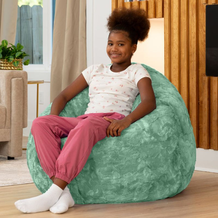 Child sitting upright in the Raven-Symoné Lil' Cuddler kids bean bag lounger in Lush Fur Spearmint Green