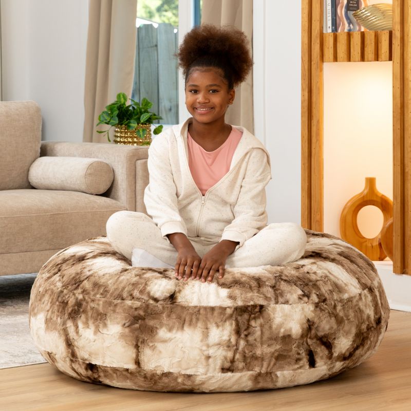 Child sitting cross-legged on the Raven-Symoné Lil' Cuddler kids bean bag lounger in Lush Tie-Dye Fur Coca Mocha