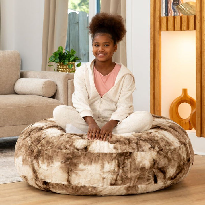 Child sitting cross-legged on the Raven-Symoné Lil' Cuddler kids bean bag lounger in Lush Tie-Dye Fur Coca Mocha