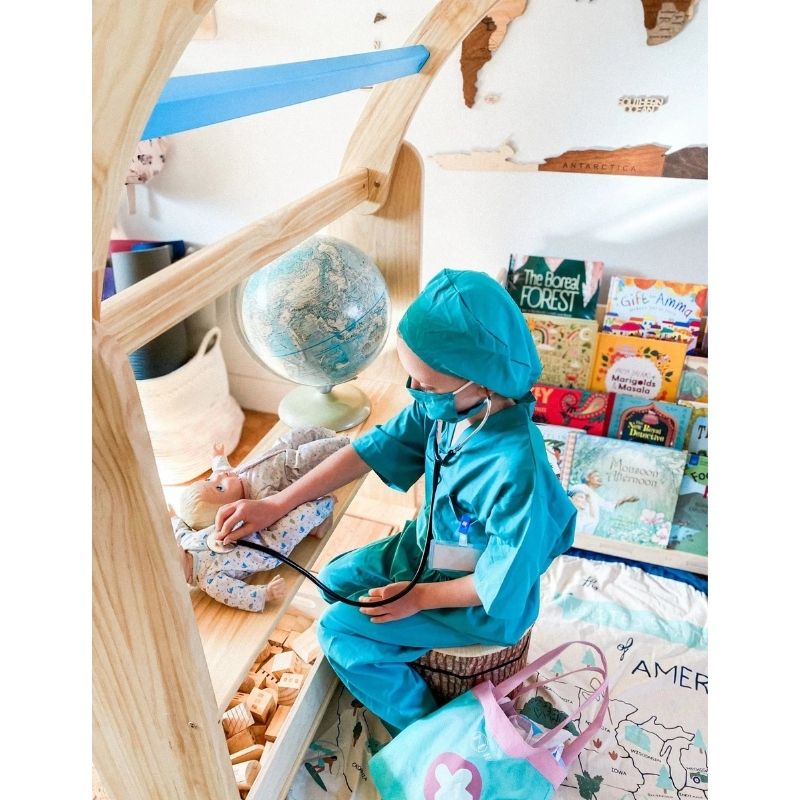 Child engaged in pretend play doctor scenario with the Kinderhuis Aurora Waldorf Playstand, showing the playstand's versatility for dramatic play